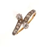 Unmarked yellow metal and diamond ring of crossover design and set two larger stones and ten