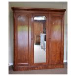 Victorian mahogany triple wardrobe having a central mirror door enclosing brushing slides and