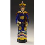 Oriental porcelain figure of a man in polychrome decorated costume holding staff, with impressed