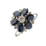 Unmarked yellow metal, diamond and sapphire cluster ring of six petal flower head design, size T½,