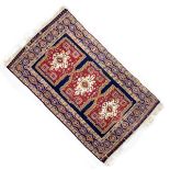 Middle Eastern wool rug, the deep-blue field with three ivory-ground medallions within deep-red