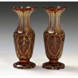 Pair of Bohemian ruby cased glass baluster shaped vases with gilt decoration, 21.5cm high