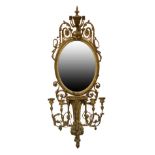 19th Century giltwood and gesso girandole wall mirror, the plain oval plate beneath urn surmount