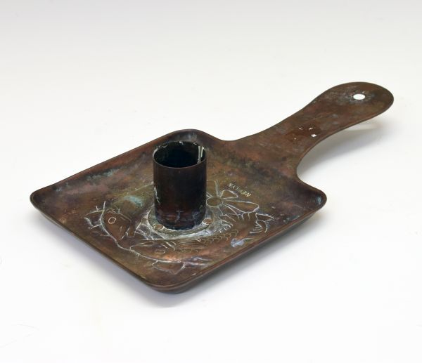 Newlyn copper chamber candlestick, having embossed decoration of two stylised fish and stamped