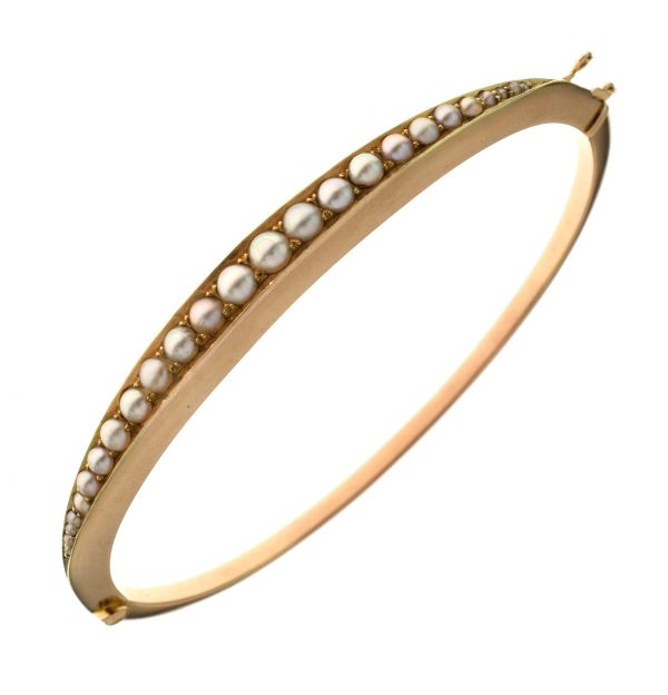 Edwardian split pearl set hinged bangle, stamped '15ct' to the catch, the frontispiece set with