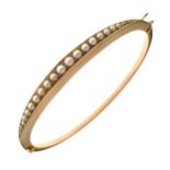 Edwardian split pearl set hinged bangle, stamped '15ct' to the catch, the frontispiece set with