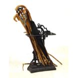 Cast iron stickstand with a selection of shooting sticks, canes, umbrella etc