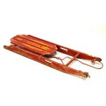 Tri-ang Flier red-painted wooden sledge with decal to seat, 105cm long