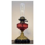 Early 20th Century brass oil or paraffin lamp with cranberry glass reservoir, 51cm high including