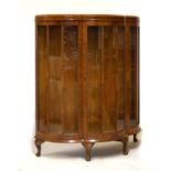 Early 20th Century walnut bow front display cabinet fitted two glass shelves enclosed by a glazed
