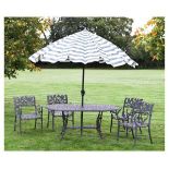 Cast metal patio set comprising table and four armchairs, and a green and white parasol