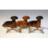 Three Beswick models of seated Dachshunds, each model 1460, together with two metal Dachshund