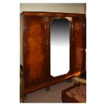 1920's period Waring & Gillows figured walnut triple wardrobe having a central mirror panel door,