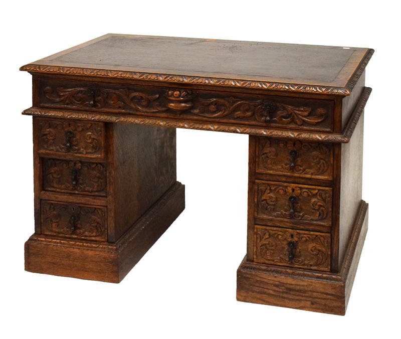 Late 19th/early 20th Century heavily carved oak twin pedestal desk fitted seven drawers, having