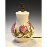 Walter Moorcroft pottery Magnolia pattern lamp of bulbous form with tube-line decoration on a