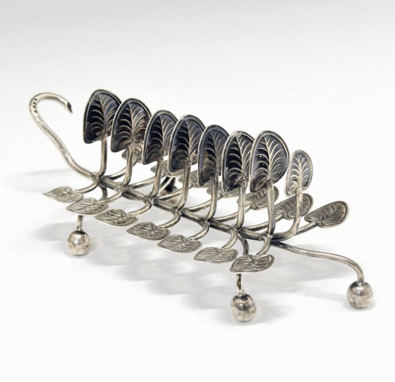 Victorian silver toast rack, having seven branches with lily pad terminals standing on four ball