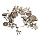 Silver curb link charm bracelet with approximately twenty-four silver and white metal charms, 2.8toz