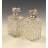 Pair of Edward VII silver top cut glass jars, the decorative covers having embossed floral