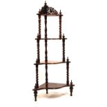 Mahogany serpentine front four-tier what-not with scroll-pierced gallery on barley twist supports,