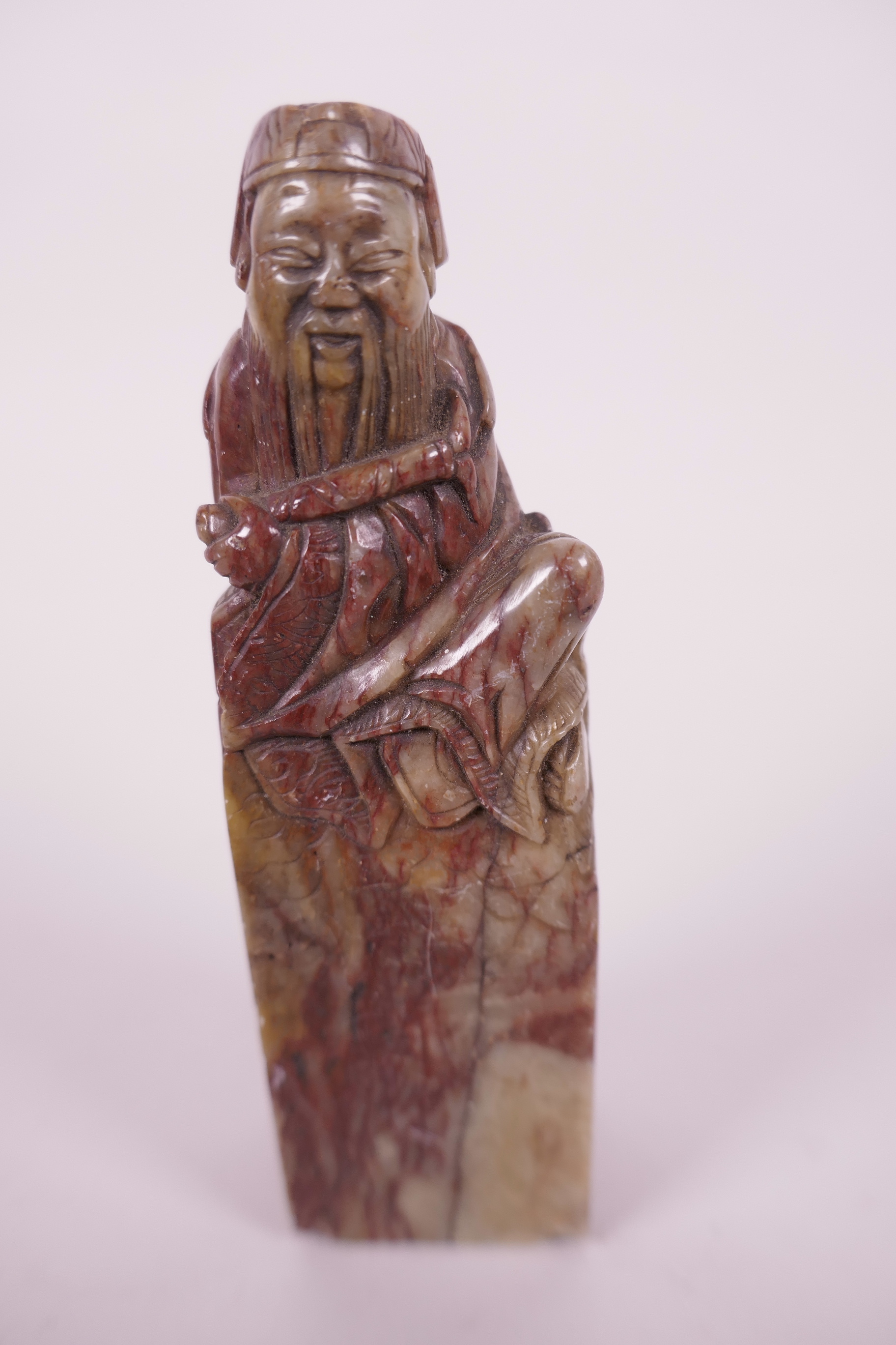 A Chinese soapstone seal carved with a seated sage, seal end blank, 4½" long