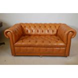 A two seater Chesterfield in orange leather, 60" x 35", 28" high
