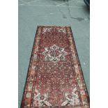 An old Persian Hamadan Luri carpet with medallion design on a tomato red field, 60" x 128"