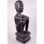 A large African wood carving of a seated figure with woven loincoth, 21½" high