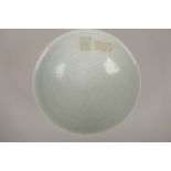 A Chinese celadon glazed pottery dish with incised decoration of boys and flowers, 8" high