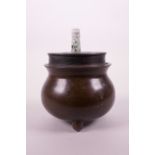 A Chinese bronze censer of cauldron form on tripod supports, with a turned hardwood lid and jade