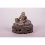 A Chinese grey soapstone carving of an emaciated deity, mounted on a carved soapstone base, 3½" wide