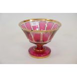 An overlaid cut cranberry glass pedestal bowl, with gilt decoration, A/F, chip to rim, 6½" high