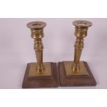 A pair of solid brass candlesticks on composition bases, 7" high