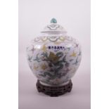 A Chinese porcelain jar and cover with Sancai enamelled dragon decoration on a carved hardwood base,