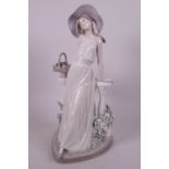 A Lladro porcelain figurine of a lady with a basket of flowers, leaning on a palisade, 13½" high
