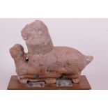 An antique unglazed terracotta figure of a lion and phoenix mounted on a wooden base, 7½" long
