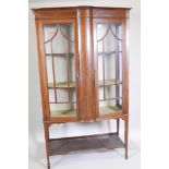 An Edwardian inlaid mahogany two door display cabinet, with shaped front, raised on square