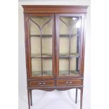 An Edwardian inlaid mahogany two door display cabinet with two drawers, raised on square tapering