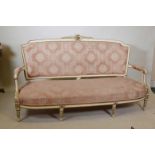 A Continental painted and parcel gilt settee, with carved crest, raised on fluted supports, 68" wide