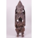 An African carved wood fertility figure of a woman feeding her baby, 13" high