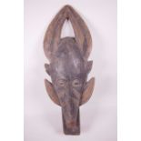 A West African carved wood tribal mask of a two horned figure, 20½" high