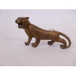 A Chinese patinated brass figure of a tiger, its coat adorned with coins, 14" long