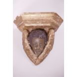 A cast plaster winged cherub wall bracket, 10" wide, 9½" high