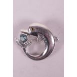 A sterling silver brooch in the form of a dolphin set with a blue topaz stone, 1"