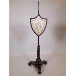 A Regency mahogany shield shaped adjustable pole screen, raised on a twisted column and platform