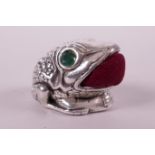 A novelty silver pin cushion in the form of a toad with emerald inset eyes, 1½"