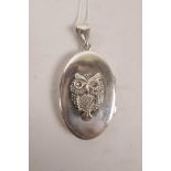 A large silver locket with applied owl decoration, on a silver chain, 1" x 1½"