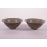 A pair of Song style olive glazed pottery bowls of conical form with raised lotus flower decoration