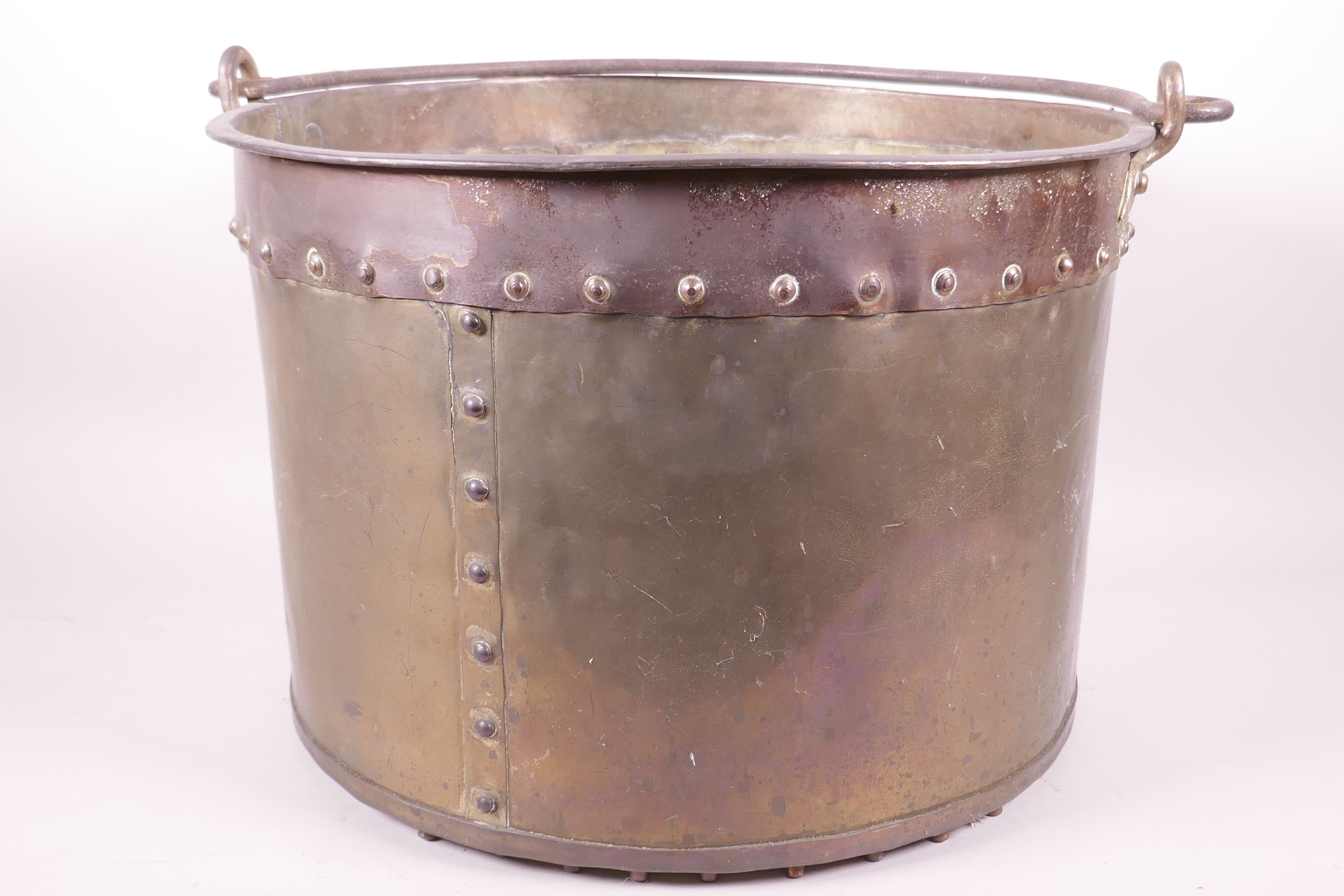 A large riveted brass bucket with iron swing handle, 14½" diameter