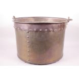 A large riveted brass bucket with iron swing handle, 14½" diameter