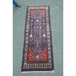 A hand woven Persian runner with a traditional diamond design on a red field and blue border, 43"